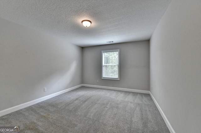 carpeted spare room with a textured ceiling, baseboards, and visible vents