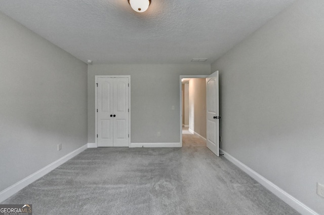 unfurnished bedroom featuring a textured ceiling, visible vents, baseboards, and carpet floors