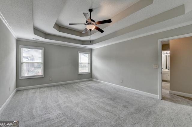 unfurnished room with a textured ceiling, a tray ceiling, a ceiling fan, and carpet