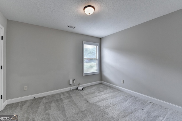 unfurnished room with carpet flooring, a textured ceiling, visible vents, and baseboards