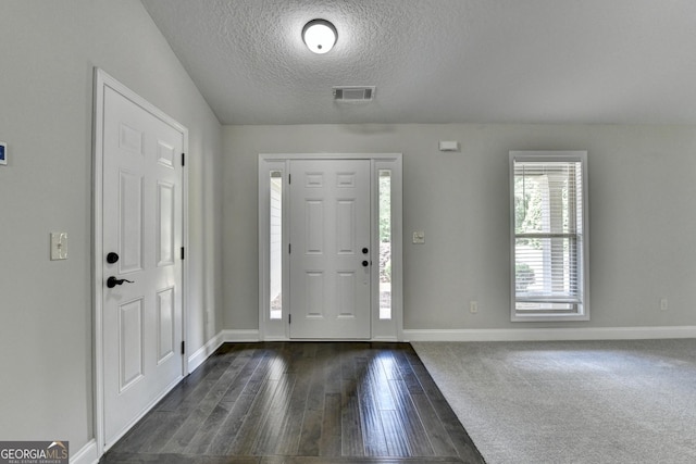 entrance foyer featuring dark wood-style flooring, a textured ceiling, visible vents, and baseboards