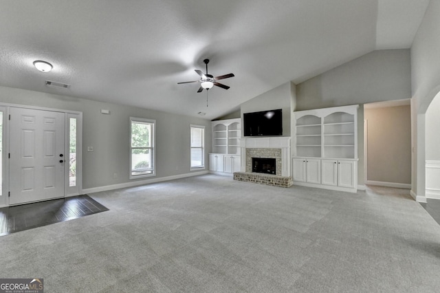 unfurnished living room with vaulted ceiling, ceiling fan, a brick fireplace, carpet floors, and baseboards