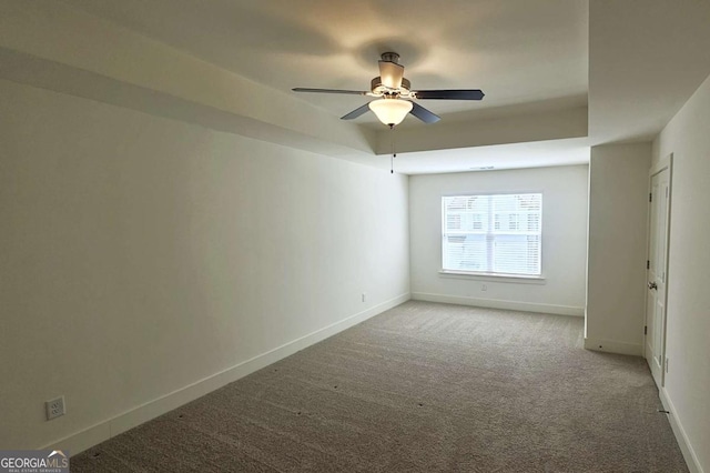 unfurnished bedroom with ceiling fan, a raised ceiling, carpet floors, and baseboards
