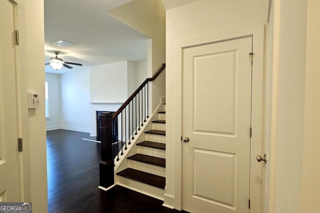staircase with a ceiling fan, baseboards, visible vents, wood finished floors, and a fireplace