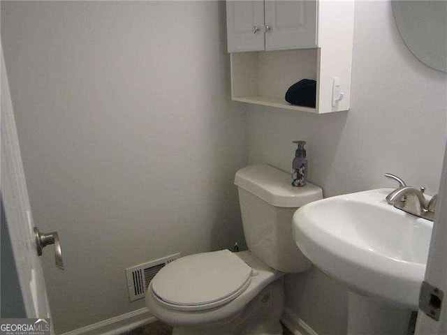 bathroom featuring toilet, visible vents, baseboards, and a sink