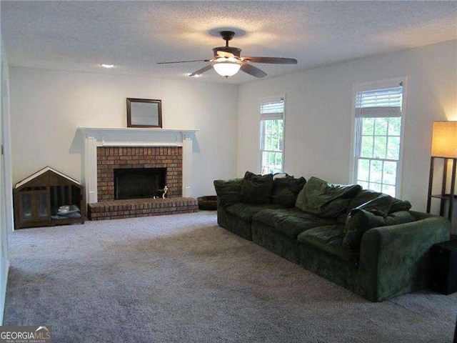 carpeted living area with a textured ceiling, a brick fireplace, and a ceiling fan