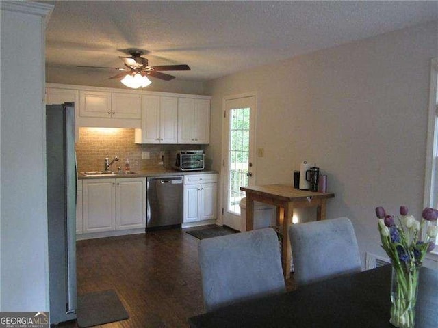 kitchen with white cabinetry, stainless steel dishwasher, backsplash, and freestanding refrigerator