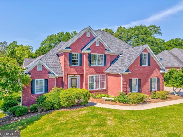 view of front of house featuring brick siding, a front lawn, and a shingled roof