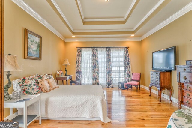 bedroom featuring a tray ceiling, wood finished floors, ornamental molding, and baseboards