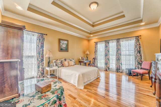 bedroom with a tray ceiling, wood finished floors, and ornamental molding