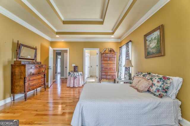 bedroom with a tray ceiling, light wood-style flooring, ornamental molding, baseboards, and recessed lighting