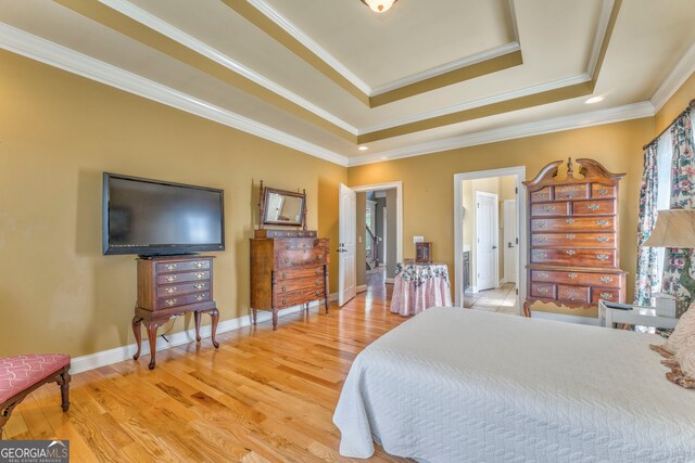bedroom with a raised ceiling, light wood-type flooring, ornamental molding, and baseboards