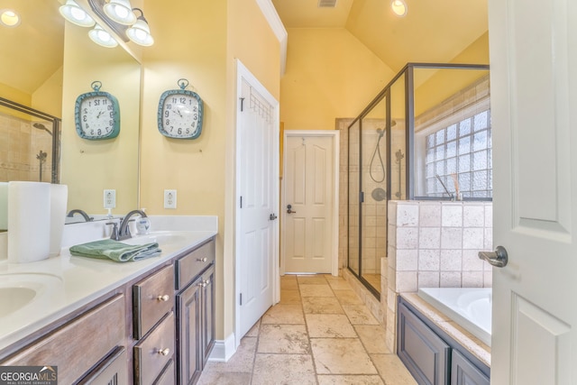 bathroom with vaulted ceiling, a shower stall, stone tile floors, double vanity, and a bath