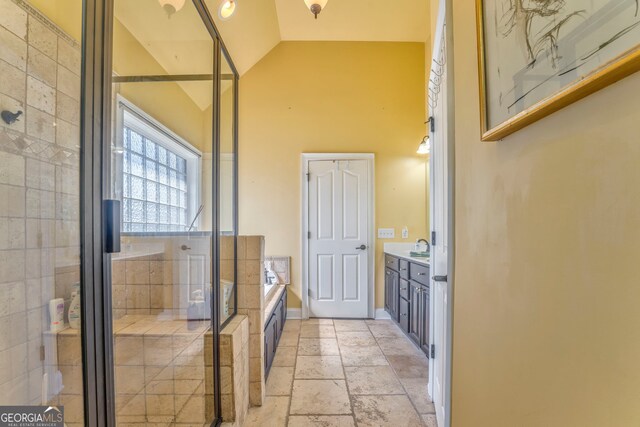 bathroom featuring vanity, a stall shower, a bath, high vaulted ceiling, and stone tile flooring