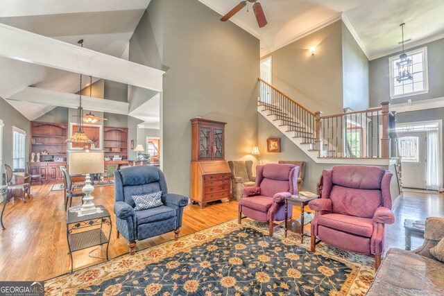 living room with high vaulted ceiling, wood finished floors, stairway, a chandelier, and crown molding