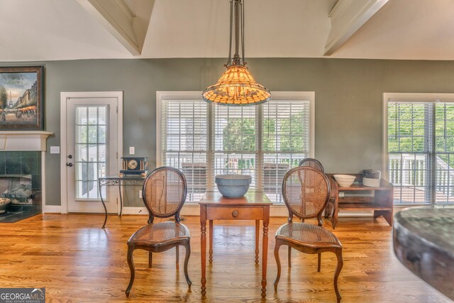 dining area with wood finished floors, healthy amount of natural light, a tiled fireplace, and baseboards