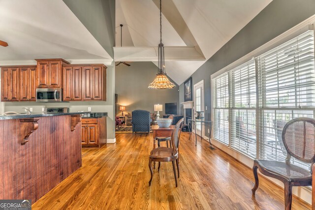 kitchen with stainless steel microwave, high vaulted ceiling, dark countertops, a kitchen breakfast bar, and open floor plan