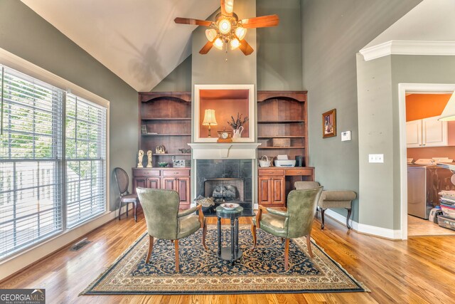 living area with washer and dryer, a ceiling fan, baseboards, a fireplace, and wood finished floors