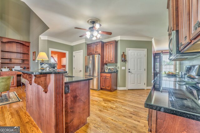 kitchen with stainless steel appliances, a kitchen breakfast bar, a ceiling fan, dark countertops, and light wood-style flooring