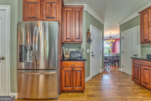 kitchen featuring stainless steel fridge with ice dispenser, light wood finished floors, crown molding, and brown cabinets