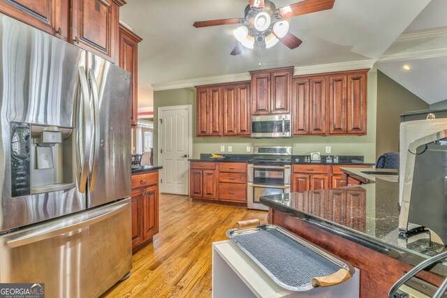 kitchen with appliances with stainless steel finishes, a ceiling fan, light wood-type flooring, ornamental molding, and a kitchen breakfast bar