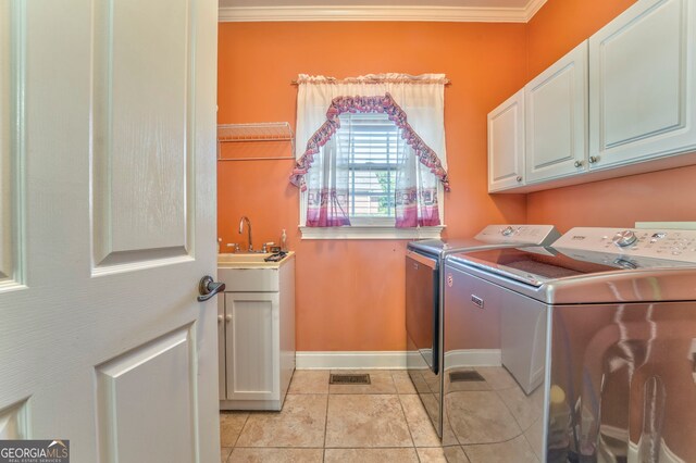 washroom featuring washer and dryer, cabinet space, crown molding, baseboards, and light tile patterned floors