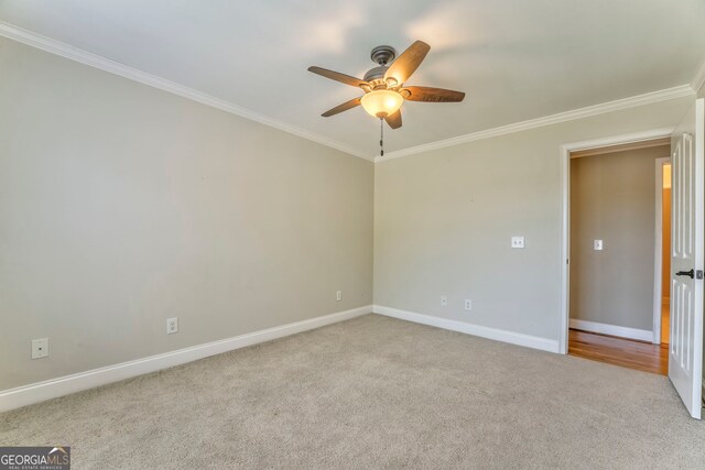 carpeted spare room featuring ceiling fan, ornamental molding, and baseboards