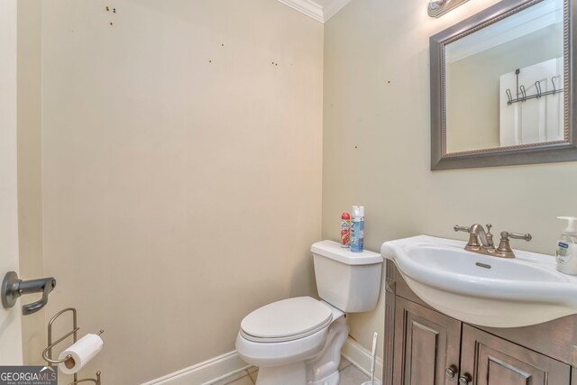 half bath with baseboards, ornamental molding, toilet, and vanity