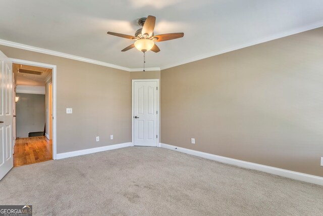unfurnished bedroom featuring crown molding, carpet, baseboards, ceiling fan, and attic access