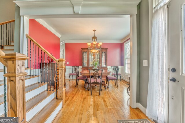dining area featuring stairway, a chandelier, light wood finished floors, and crown molding