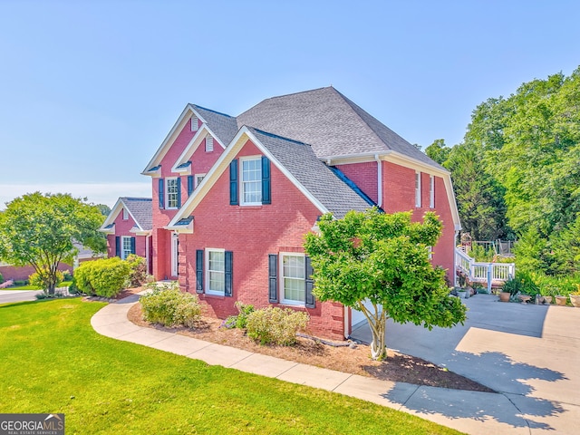 view of front of house with brick siding, a front lawn, and driveway
