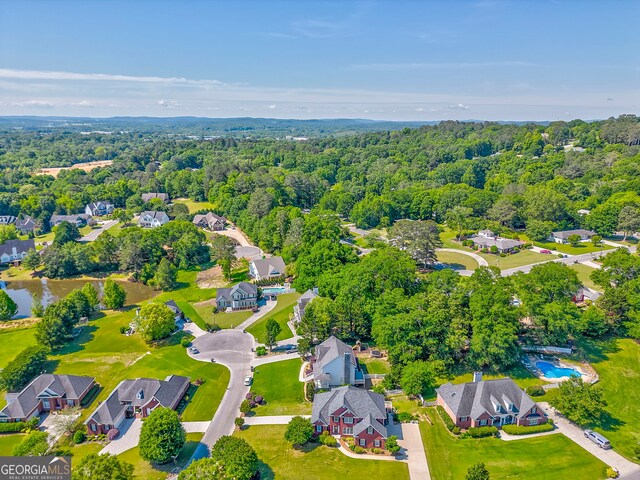 aerial perspective of suburban area featuring a forest and a nearby body of water