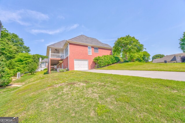 view of side of home with ceiling fan, concrete driveway, a garage, a lawn, and brick siding