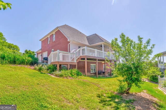 back of house with a deck, a yard, and brick siding