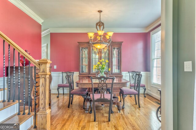 dining space with a chandelier, crown molding, wood finished floors, a wainscoted wall, and stairs
