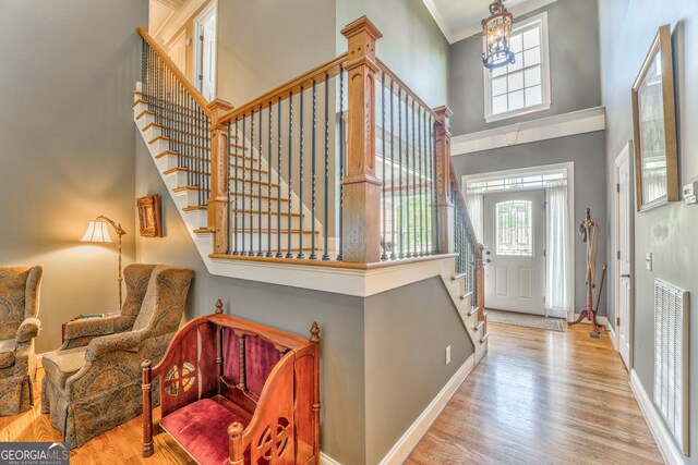 foyer entrance featuring a high ceiling, stairs, healthy amount of natural light, and wood finished floors
