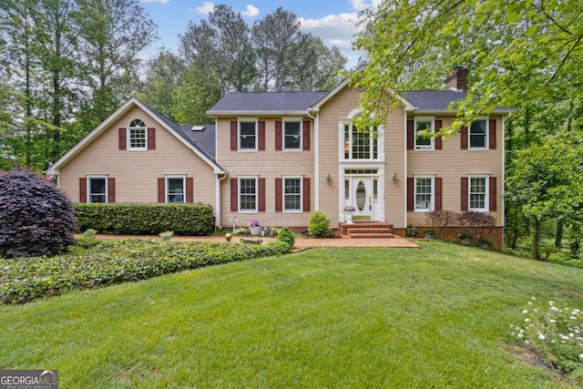 colonial home featuring a front lawn and a chimney
