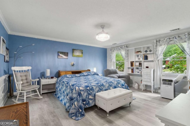 bedroom featuring ornamental molding, visible vents, and wood finished floors
