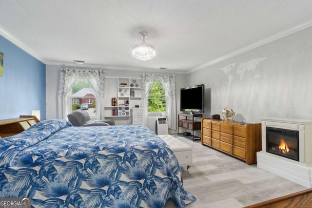 bedroom featuring light wood finished floors, multiple windows, ornamental molding, and a glass covered fireplace