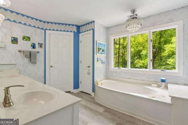 bathroom with a garden tub, double vanity, wood finished floors, a sink, and a notable chandelier