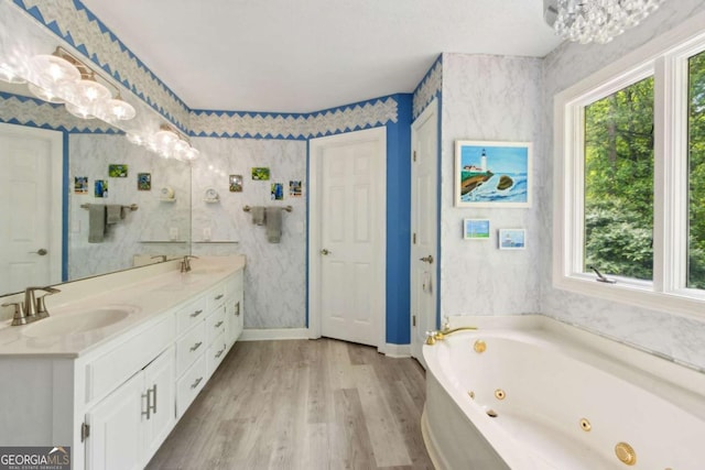 bathroom featuring a healthy amount of sunlight, an inviting chandelier, a sink, and wood finished floors