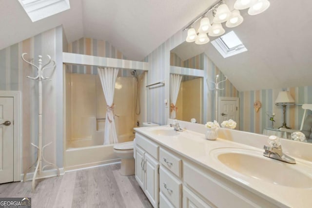 full bathroom with a sink, lofted ceiling with skylight, wallpapered walls, and wood finished floors