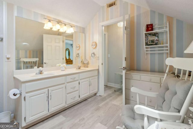 bathroom with wallpapered walls, visible vents, wood finished floors, and a sink