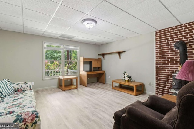living room featuring a drop ceiling, a wood stove, and wood finished floors