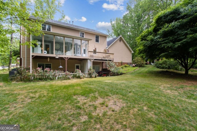 back of property featuring central AC unit, a sunroom, a deck, and a lawn