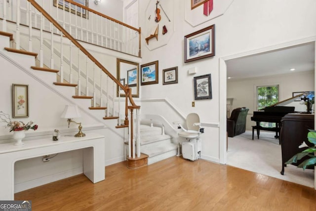 staircase featuring a towering ceiling and wood finished floors