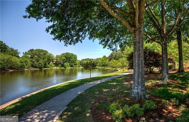 surrounding community with a water view, a lawn, and a view of trees