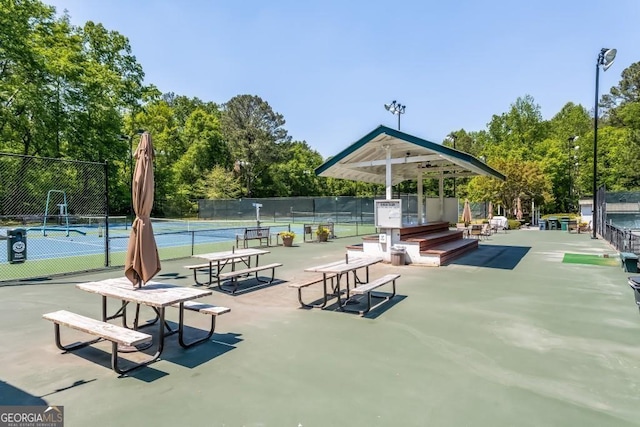 view of community with a tennis court and fence