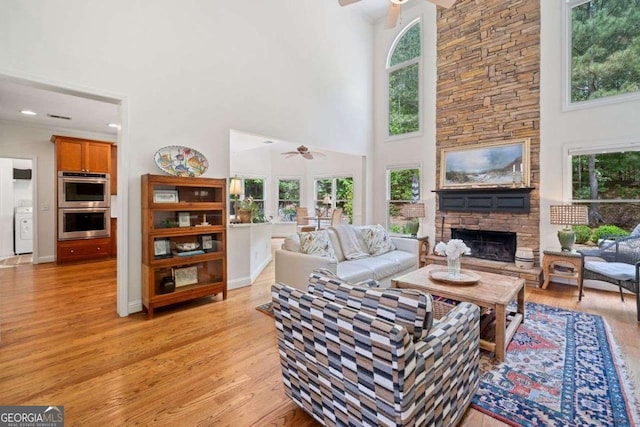 295 River Laurel Way, Woodstock, GA 30188 - living room featuring a ceiling fan, washer / clothes dryer, light wood finished floors, a fireplace, and a high ceiling
