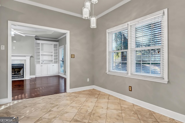176 Fairethorne Dr, Leesburg, GA 31763 - unfurnished dining area featuring ceiling fan with notable chandelier, built in features, a fireplace, crown molding, and baseboards